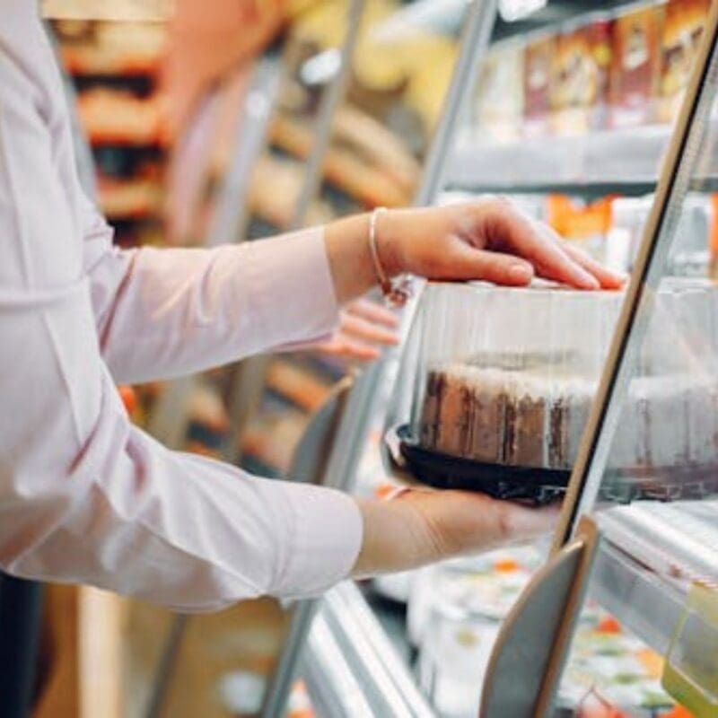 staff grabbing a cake from cake display cabinet