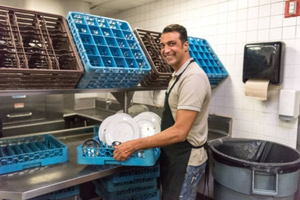 a happy staff working in a kitchen with dishwasher